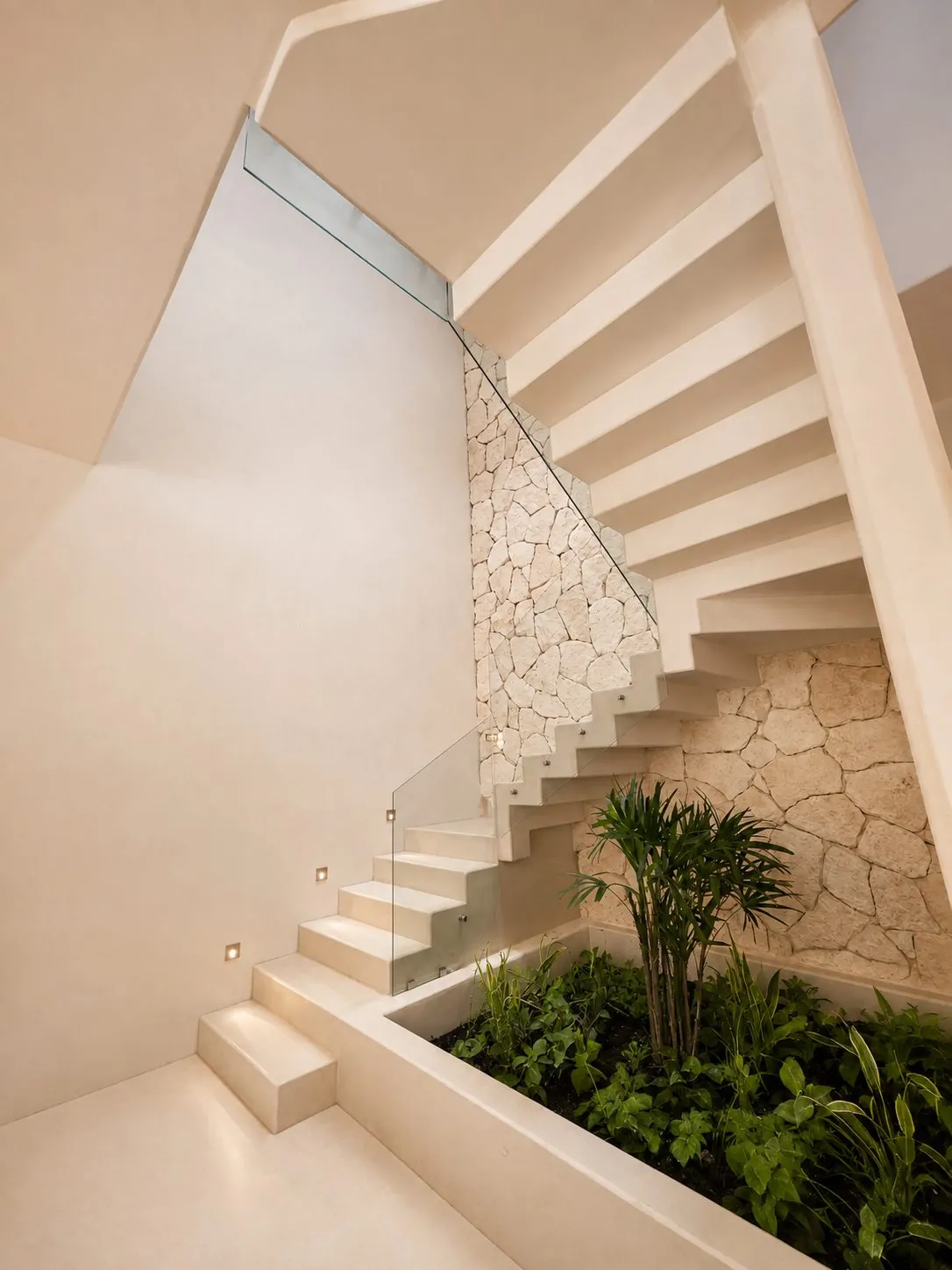 Escalera escultórica con muro de piedra y jardín interior en Casa Aria